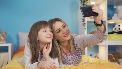 Little-girl-and-her-mother-are-video-chatting-on-the-phone-on-the-bed-in-the-nursery.